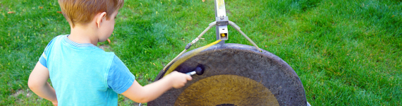 Ein Junge spielt auf einem Gong, der im Wasser steht