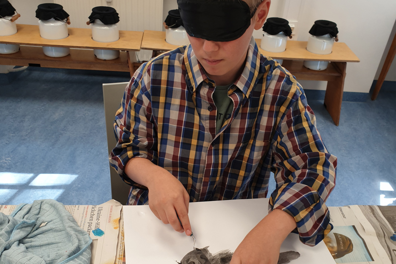 ein Junge mit Augenbinde malt ein Bild