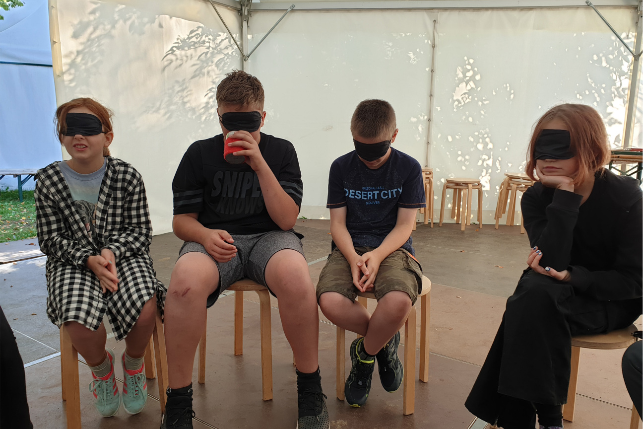 Kinder mit Augenbinden riechen an einer Dose