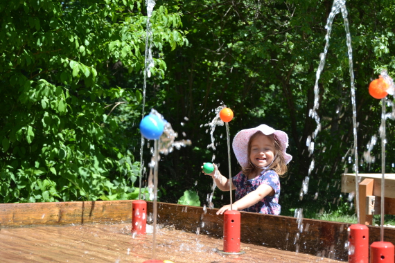 ein kleines Mädchen spielt mit Bällen im Wasser