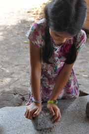Mädchen zermahlt Körner mit einem Stein