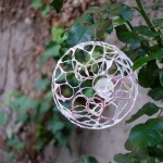 Eine Kugel aus Draht und Papier hängt auf einem Baum