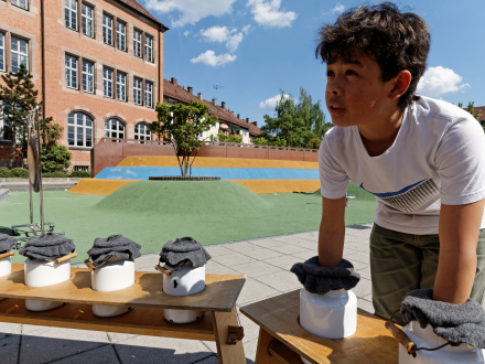 Foto von einem Kind. Das Kind steckt seine Hände in 2 Gefäße. Das Kind ertastet die Dinge in den Gefäßen., Bild © Karl-Friedrich Hohl / Stadt Nürnberg