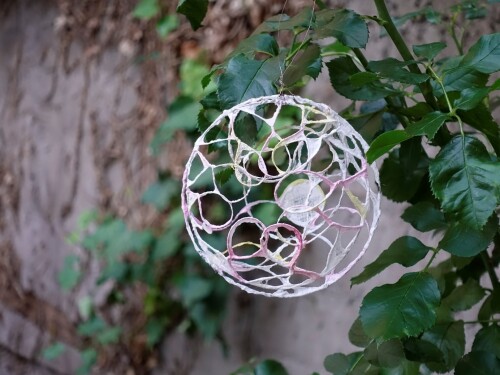 © Lisa Metz Eine Kugel aus Draht und Papier hängt auf einem Baum © Lisa Metz