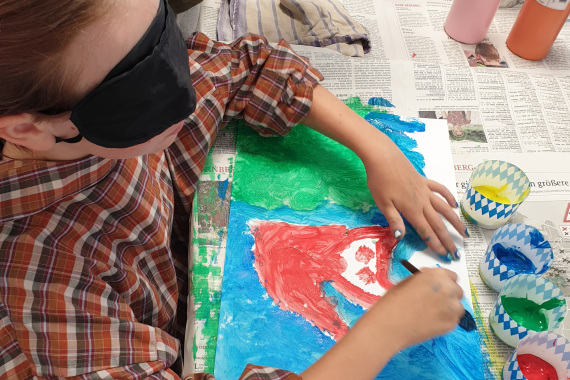 Ein Mädchen mit Augenbinde malt ein Bild