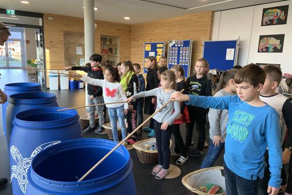 Kinder angeln Müll aus Plastiktonnen
