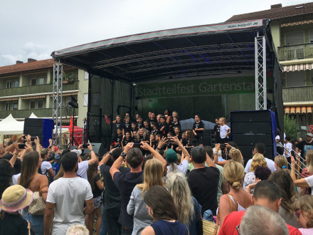 Foto: Eine Bühne bei einem Stadt·teil·fest. Vor der Bühne stehen viele Personen. © Amt für Kultur und Freizeit