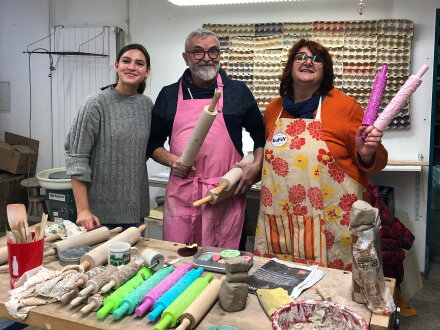 Foto von 3 Personen bei einem Töpfer·kurs. Vor den Personen steht ein Tisch mit Werkzeugen fürs Töpfern. 2 von den 3 Personen haben eine Schürze an und halten ein Werkzeug in der Hand., Bild © Anna-Maria Fehle / Kulturladen Gartenstadt