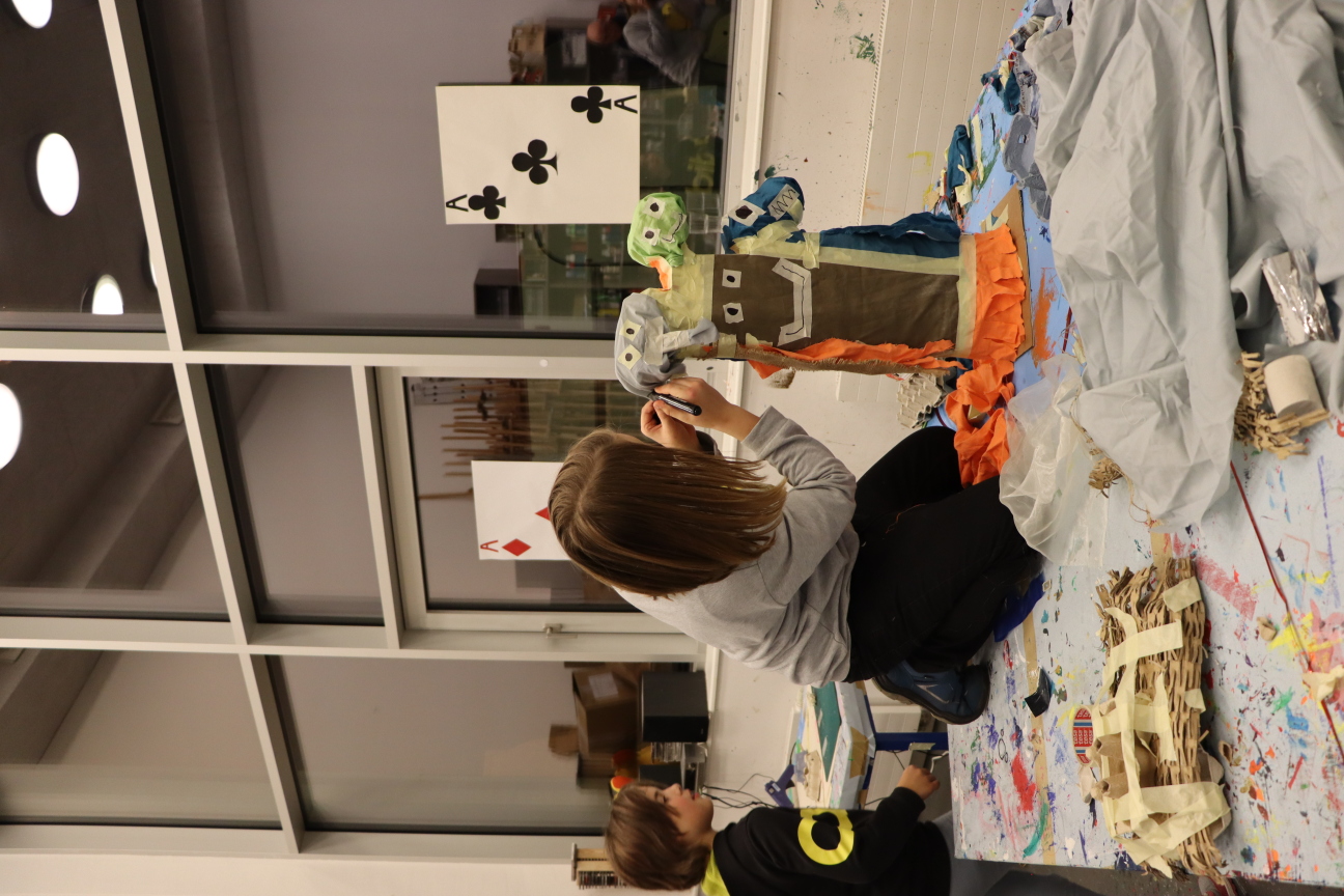 Kind baut an einer Figur aus Karton und Stoff