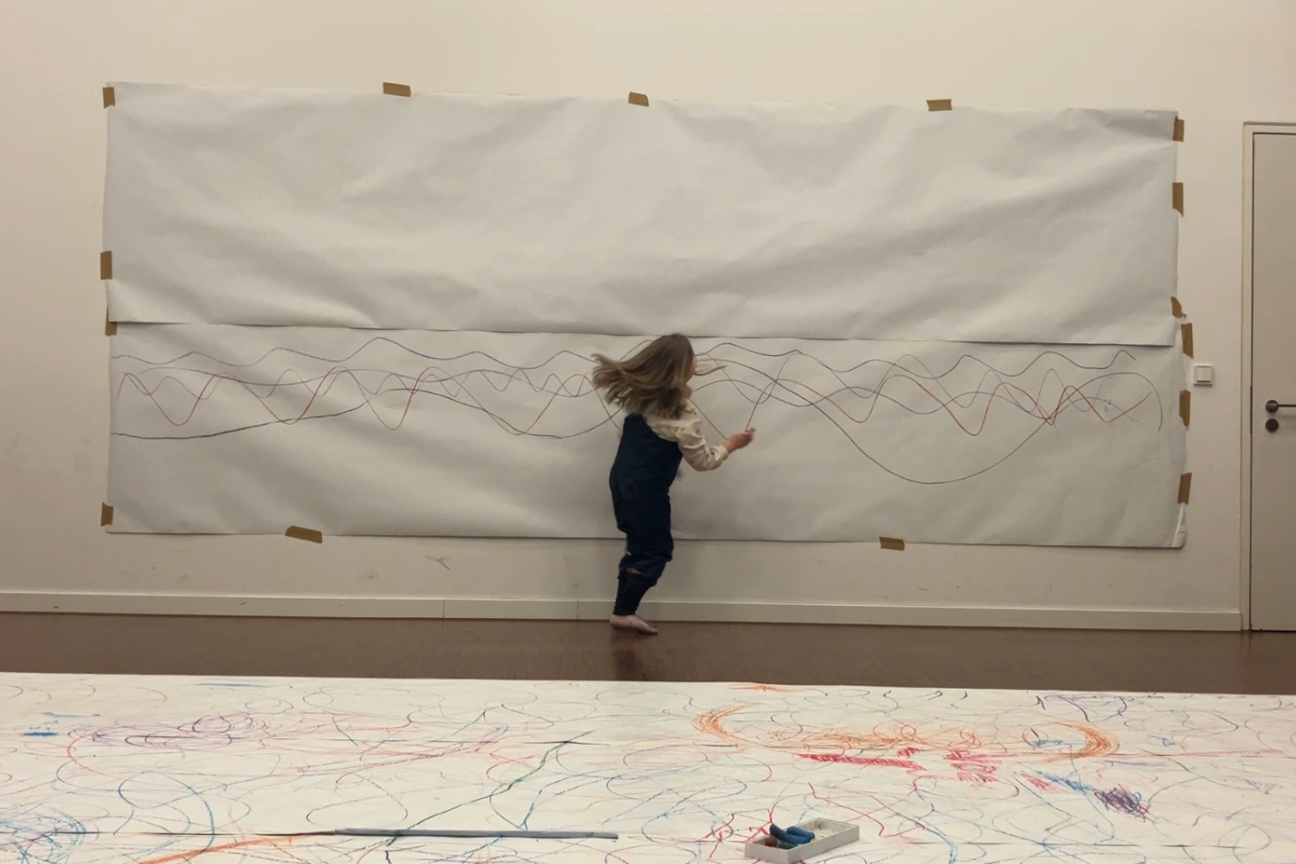 Kind malt mit Wachsmalkreide auf Papierbahn auf Wand, Bild © KinderKunstRaum / Stadt Nürnberg