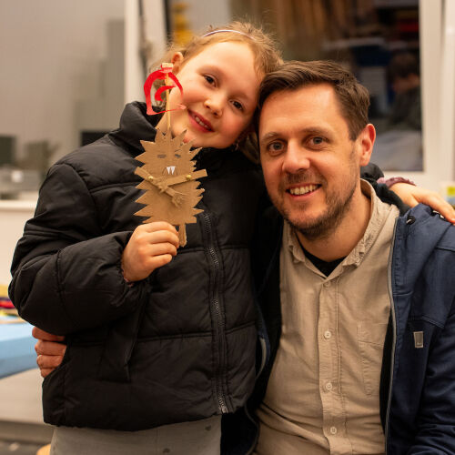 Kind hält selbst gemachte Figur und umarmt Vater