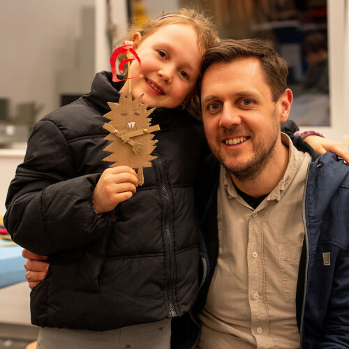 Kind hält selbst gemachte Figur und umarmt Vater