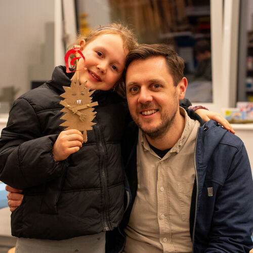 Kind hält selbst gemachte Figur und umarmt Vater