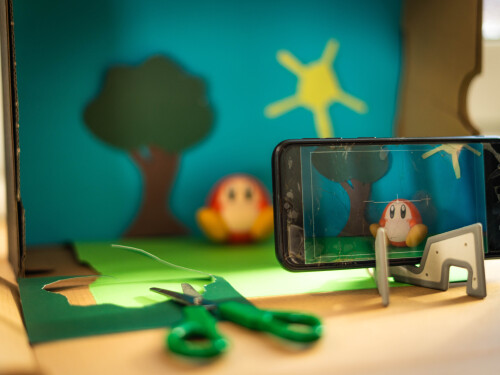 Knetwesen in Schuhkarton-Landschaft wird mit Handy gefilmt