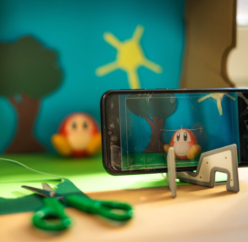 Knetwesen in Schuhkarton-Landschaft wird mit Handy gefilmt