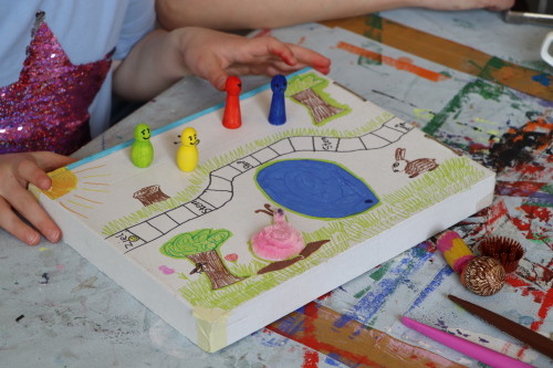 Kind spielt mit selbst gestaltetem Brettspiel