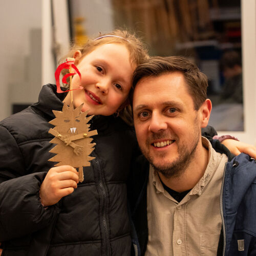 Kind hält selbst gemachte Figur und umarmt Vater