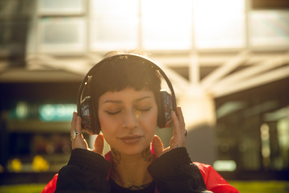 Beautiful woman listening music with headphone outdoor in the city