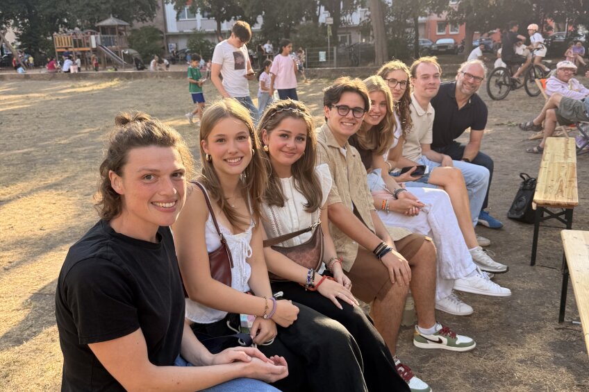 Eine Gruppe von Jugendlichen sitzt auf einer Bank im Park und lächelt in die Kamera, Bild © RadioPhil