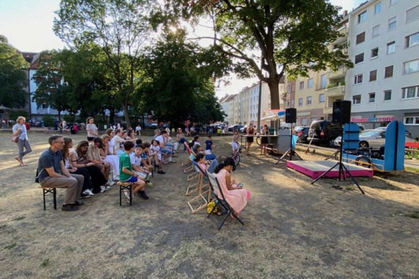 Menschen sitzen vor einer mobilen Bühne im Park, Bild © Maria Beyer