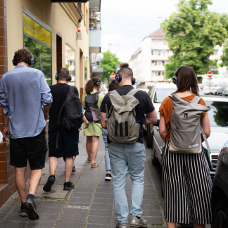 ( Bild: Oleksandra Shyshlakova / Stadt Nürnberg ) Mehrere Personen mit Kopfhörern laufen durch die Straße