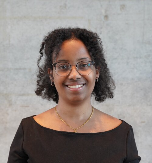 Frau lächelt mit schwarzem Oberteil und grauem Hintergrund