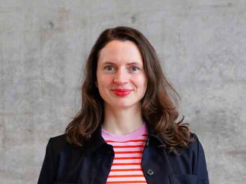 Frau mit rosa rotem Oberteil steht vor grauem Hintergrund und lächelt in die Kamera © Hager / Stadt Nürnberg