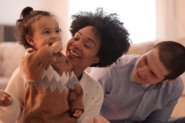 Move Happy Familientanznachmittage, zwei Eltern und ein Kind lachen zusammen und tanzen