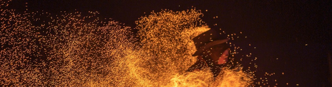 Funken eines Feuerstabes in Orange vor schwarzer Nacht zu sehen.