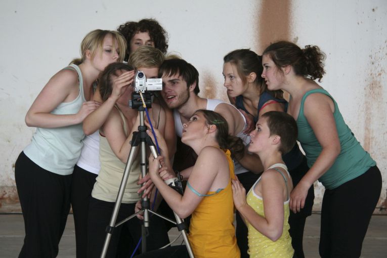 Gruppe in Sportkleidung schaut gemeinsam in eine Videokamera.
