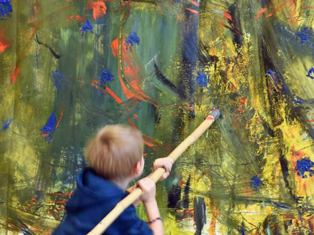 Foto von einem Kind beim Malen auf einer großen Leinwand., Bild © KinderKunstRaum / Stadt Nürnberg