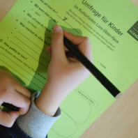 Kinderumfrage im KUF, ein Kind füllt einen Umfragebogen aus.