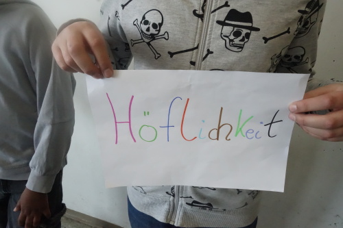 Höflichkeit und Fairness -  so geht Respekt. Ein Kind zeigt ein selbstgebasteltes Plakat zum Thema Höflichkeit, das im Rahmen der Nürnberger Wochen gegen Rassismus entstanden ist.