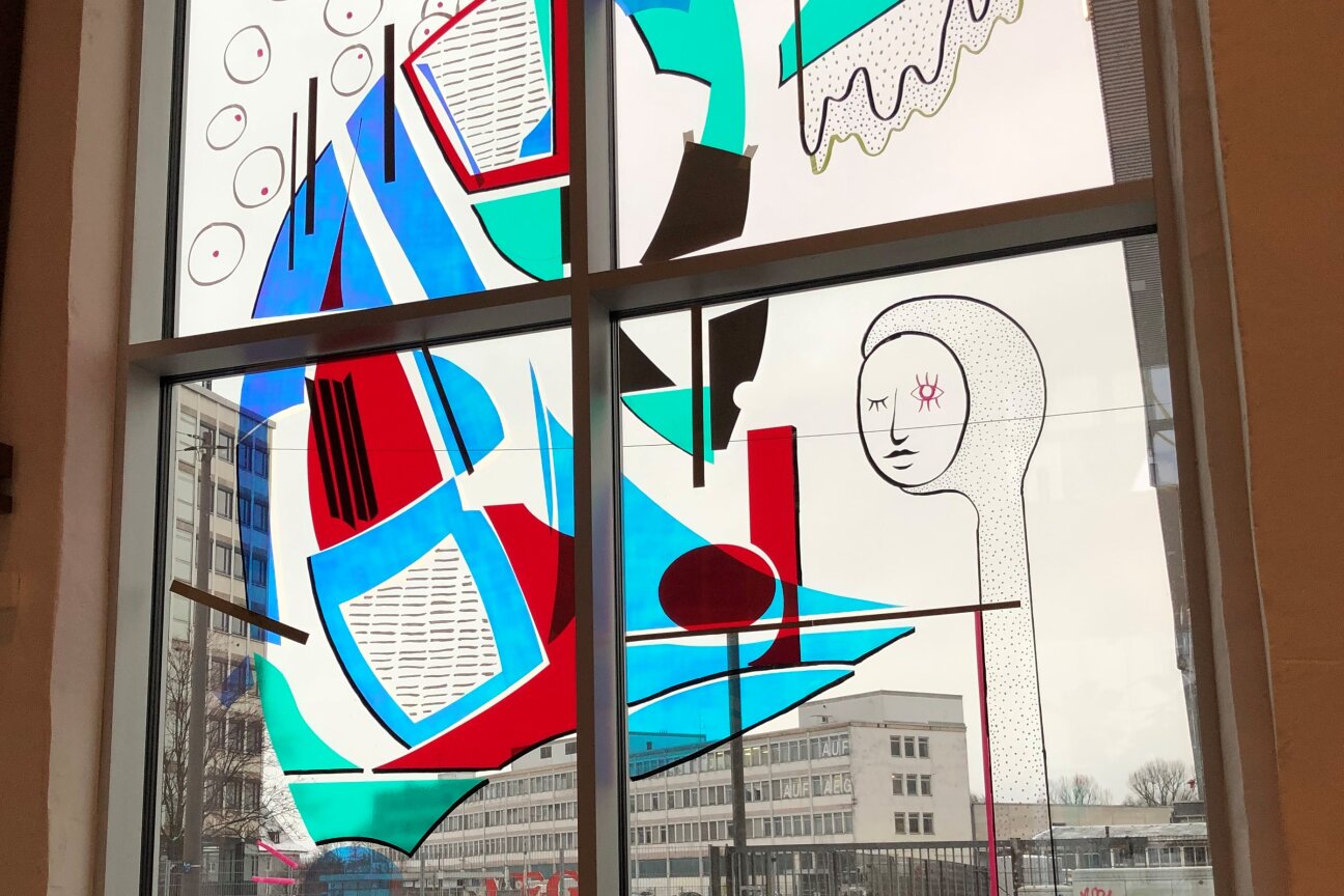 Zwei Künstler bekleben eine Scheibe