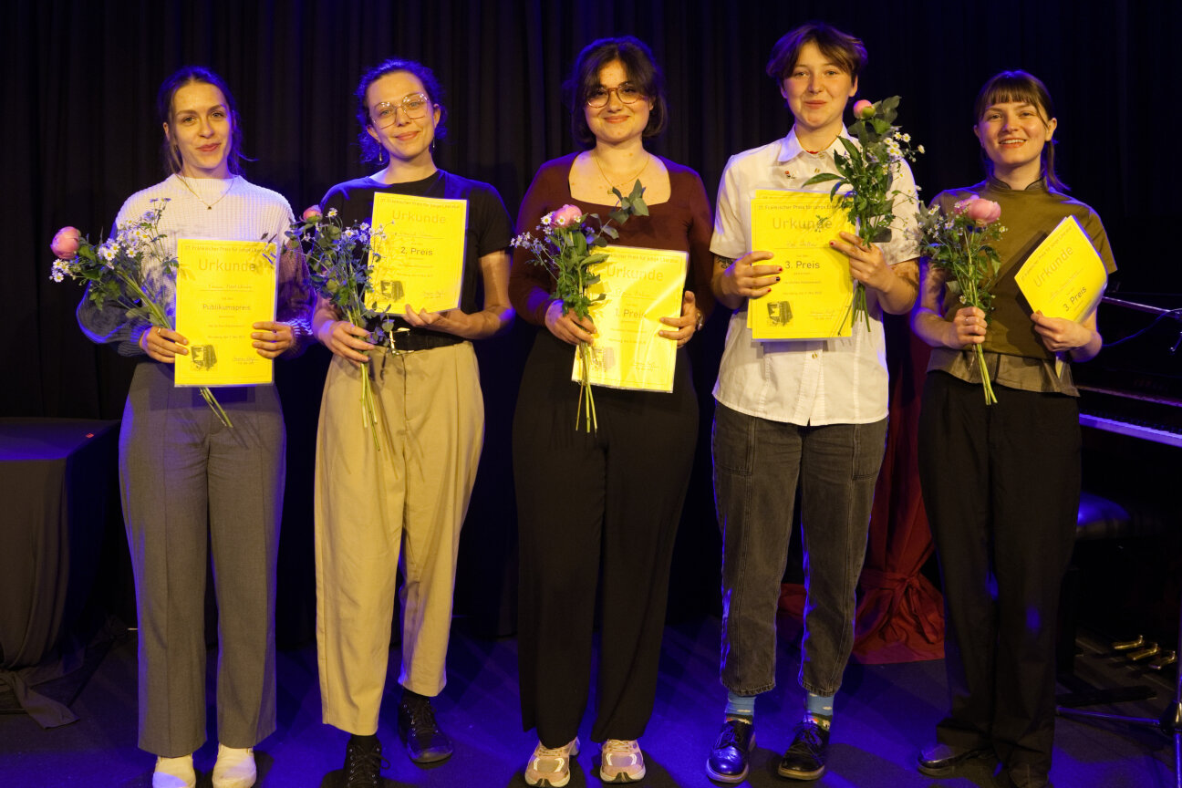 Fünf junge Menschen stehen auf einer Bühne, sie halten Urkunden und Blumen in den Händen