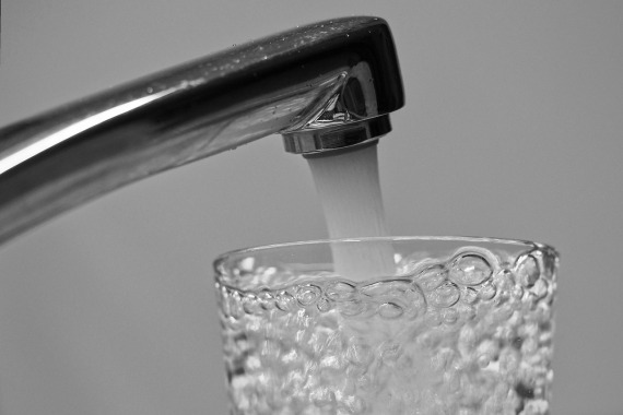 Aus einem silbernen Wasserhahn läuft Wasser in ein Glas