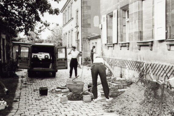 Bauarbeiter bearbeiten Weg aus Pflastersteinen vor altem Gebäude