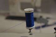 Eine blaue Garnrolle auf einer Nähmaschine