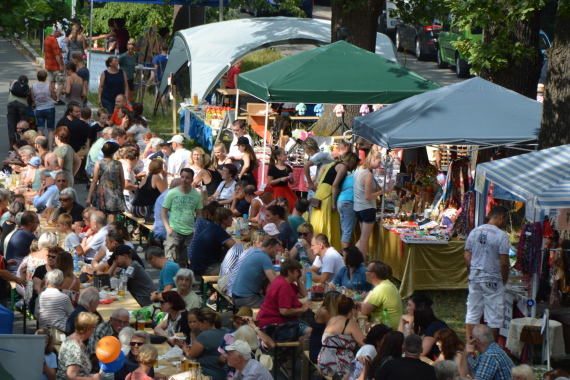 Biertische mit vielen Menschen und Infostände mit bunten Schirmen