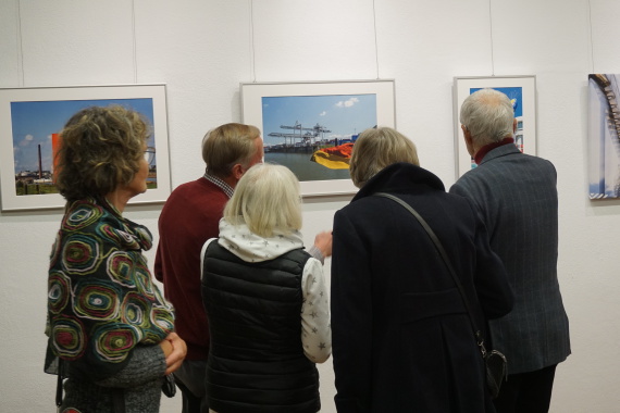 Fünf Personen stehen vor Bildern einer Ausstellung und unterhalt
