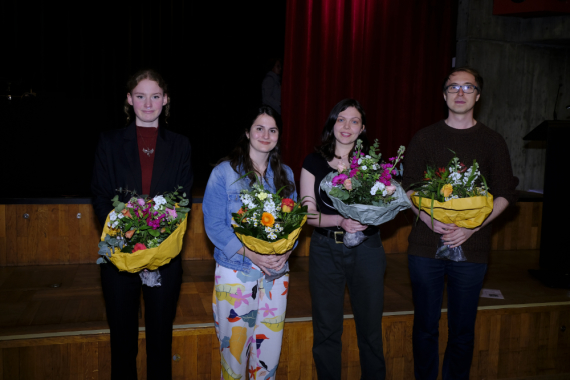 Vier junge Frauen und ein junger Mann stehen mit großen Blumensträußen auf einer Bühne