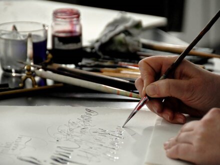 Foto von Händen von einer Person. Die Person macht Kalligraphie. Kalligraphie ist die Kunst vom schönen Schreiben., Bild © Karin Thrän / Stadt Nürnberg