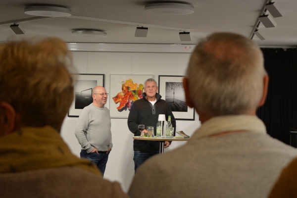 zwei Männer stehen an einem Tisch vor ihren Kunstwerken and der Wand