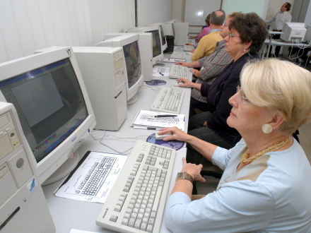 Foto von mehreren Menschen an einem langen Schreib∙tisch. Die Menschen machen etwas am Computer., Bild © Claus Felix