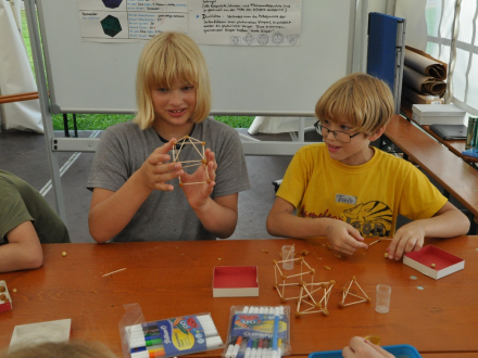 Foto von 2 Kindern an einem Tisch. Die Kinder basteln mit Holz∙stäbchen., Bild © Stadt Nürnberg