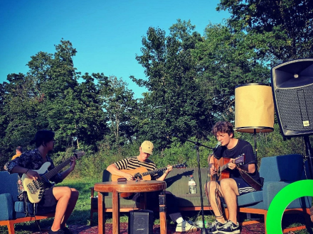 Foto von 3 Personen in einem Park. Die Personen sitzen auf Sesseln. Jede Person spielt auf einer Gitarre. Die Person rechts hat ein Mikrofon vor sich., Bild © Stadt Nürnberg