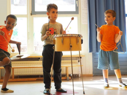 Foto von 3 Kindern mit Instrumenten. Das Kind links hat eine Becken·scheibe und einen Trommel·stock. Das Kind in der Mitte hat eine Trommel. Und das Kind rechts hat eine Triangel., Bild © Stadt Nürnberg, MUBIKIN
