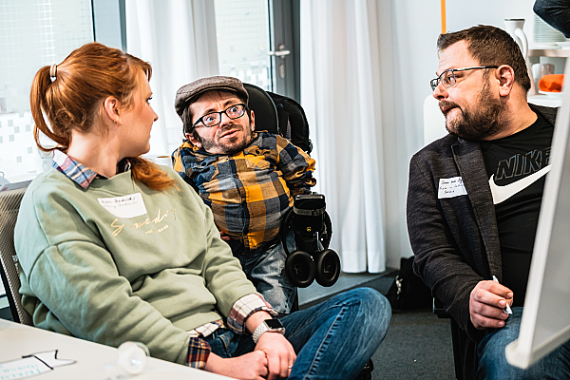 Foto von 3 Personen bei einer Besprechung.