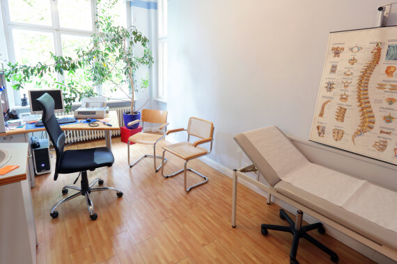 Foto von einem Sprech·zimmer mit einer Untersuchungs·liege.