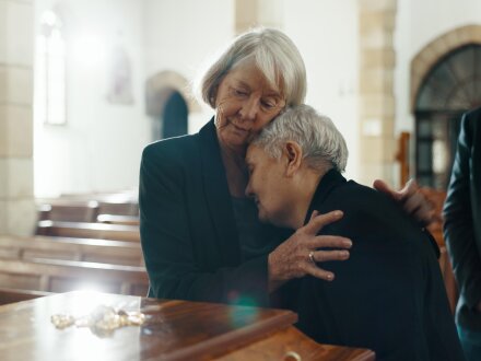 Foto von 3 älteren Personen bei einer Bestattung.